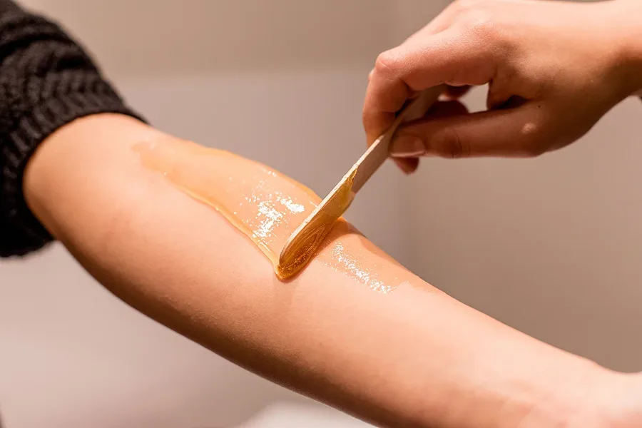 Professional waxing application on arm